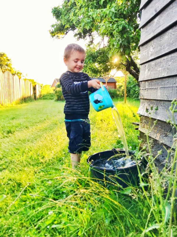 kid outside filling bucket with water