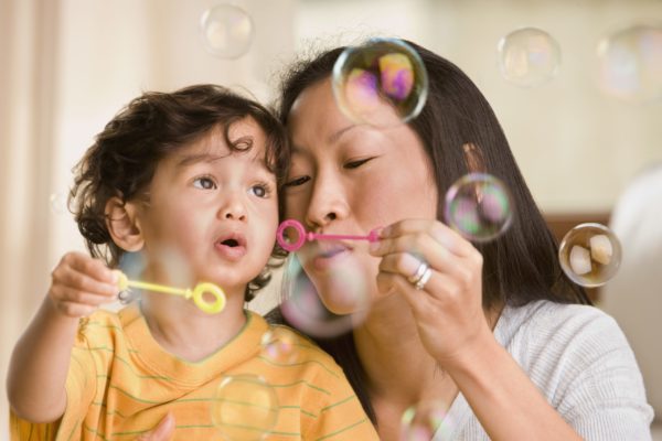 Mother blowing bubbles with child.
