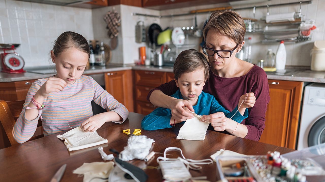 Mother making a face covering with two children.