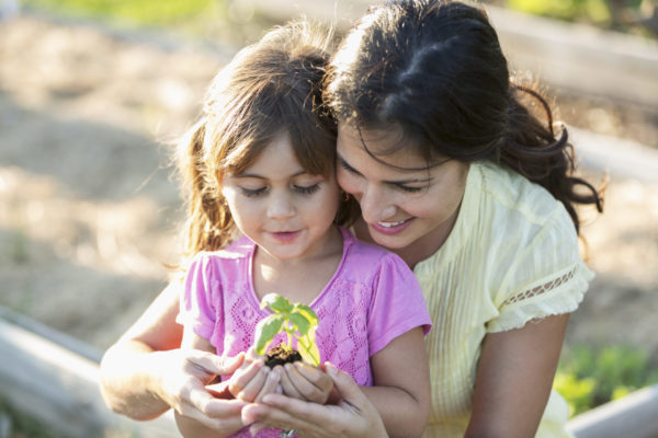 Mother with little girl and small plant.