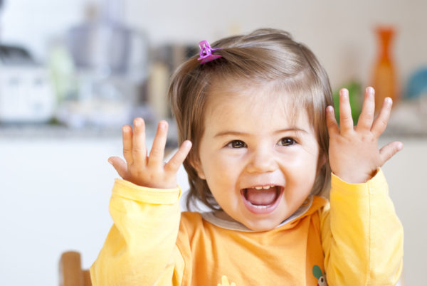 Little girl holding hands up and smiling.